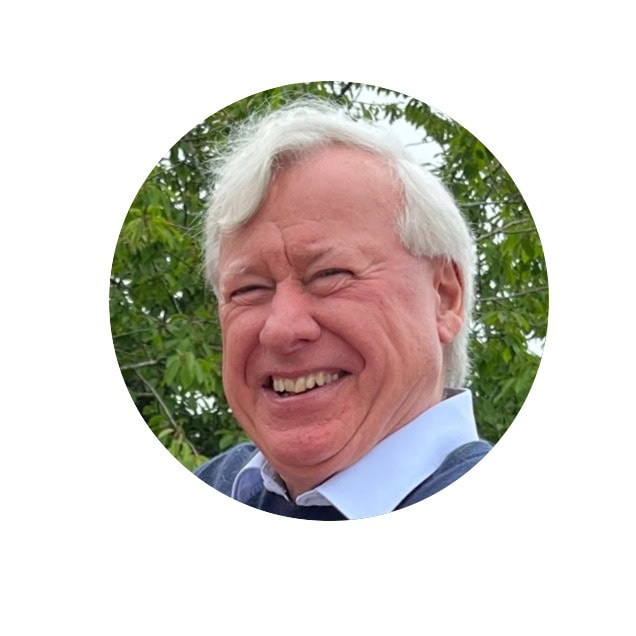 a portrait of Mark Loveday laughing in front of some greenery.