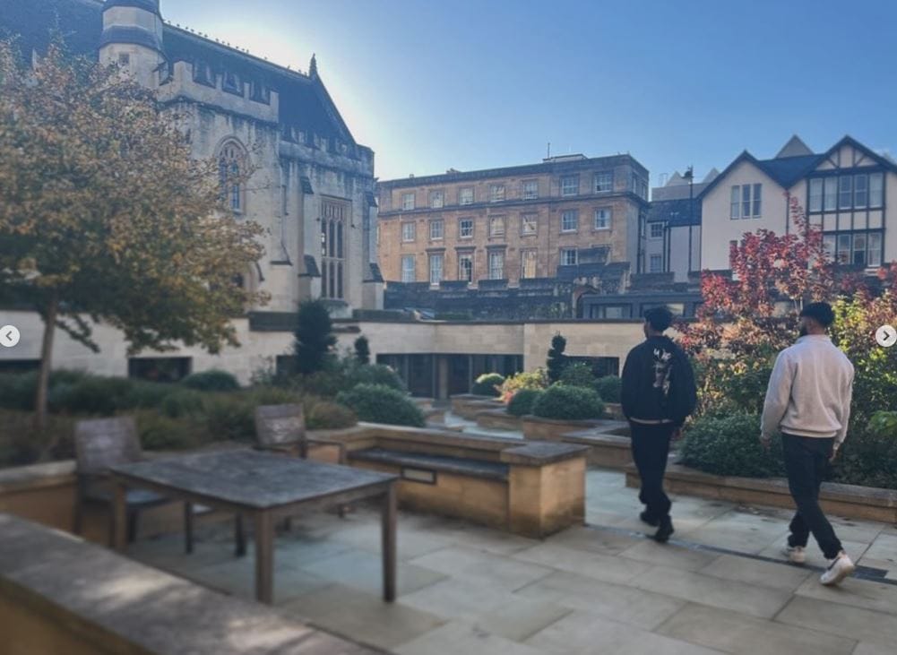 two students walk down the steps towards Longwall library on a bright, sunny, autumnal day. The sky is cloudless