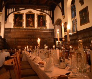 Magdalen Hall lit by candles and arranged for a formal, with silverware and napkins.