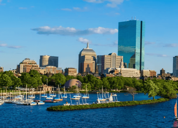 A view of Boston skyline in the background, with riverside quay and boats in the foreground