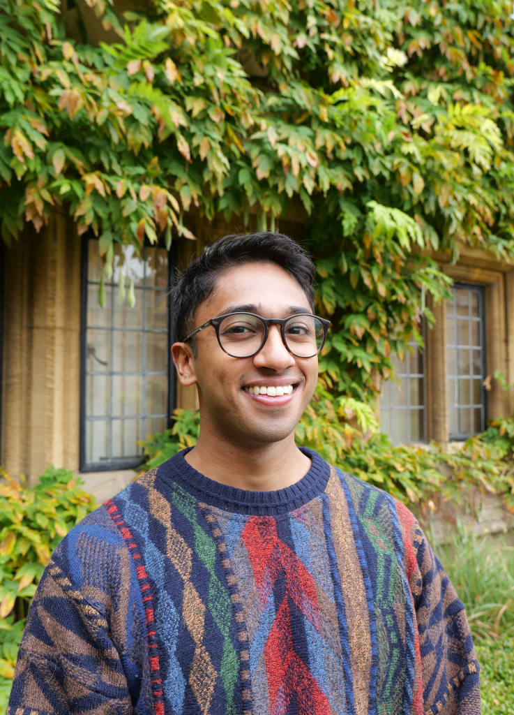 a portrait of Ragy smiling wearing a snazzy jumper