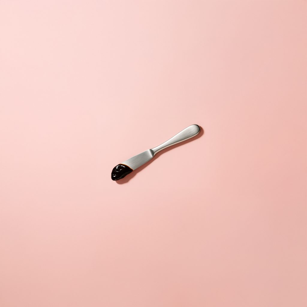 Spoon with Marmite of pink background
