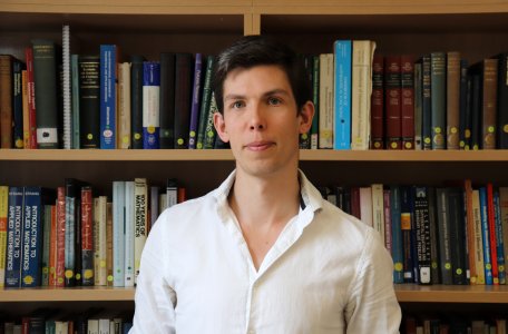 James Maynard in front of bookshelf