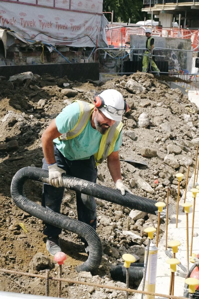 A construction worker installs underground piping.